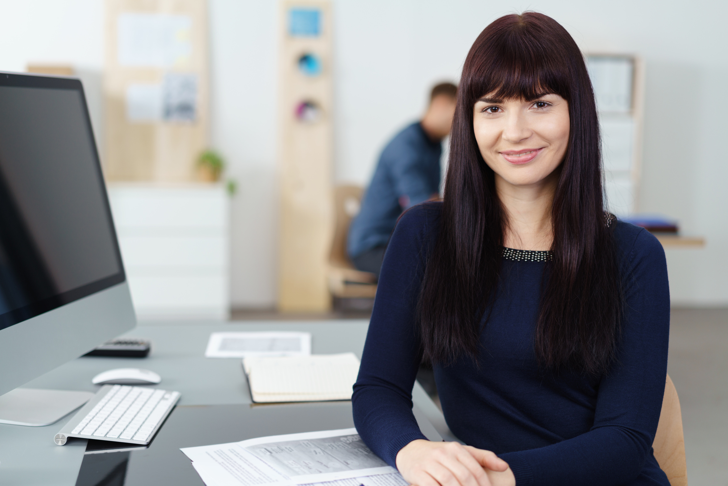 freundliche mitarbeiterin arbeitet im büro am pc